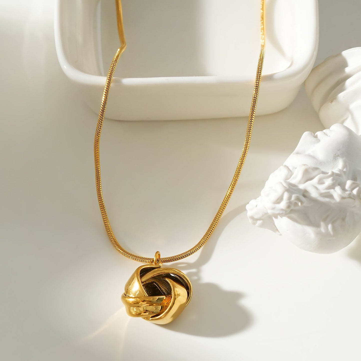 JASPUR: Snakeskin Chain Necklace with Love-Knot Pendant in Gold