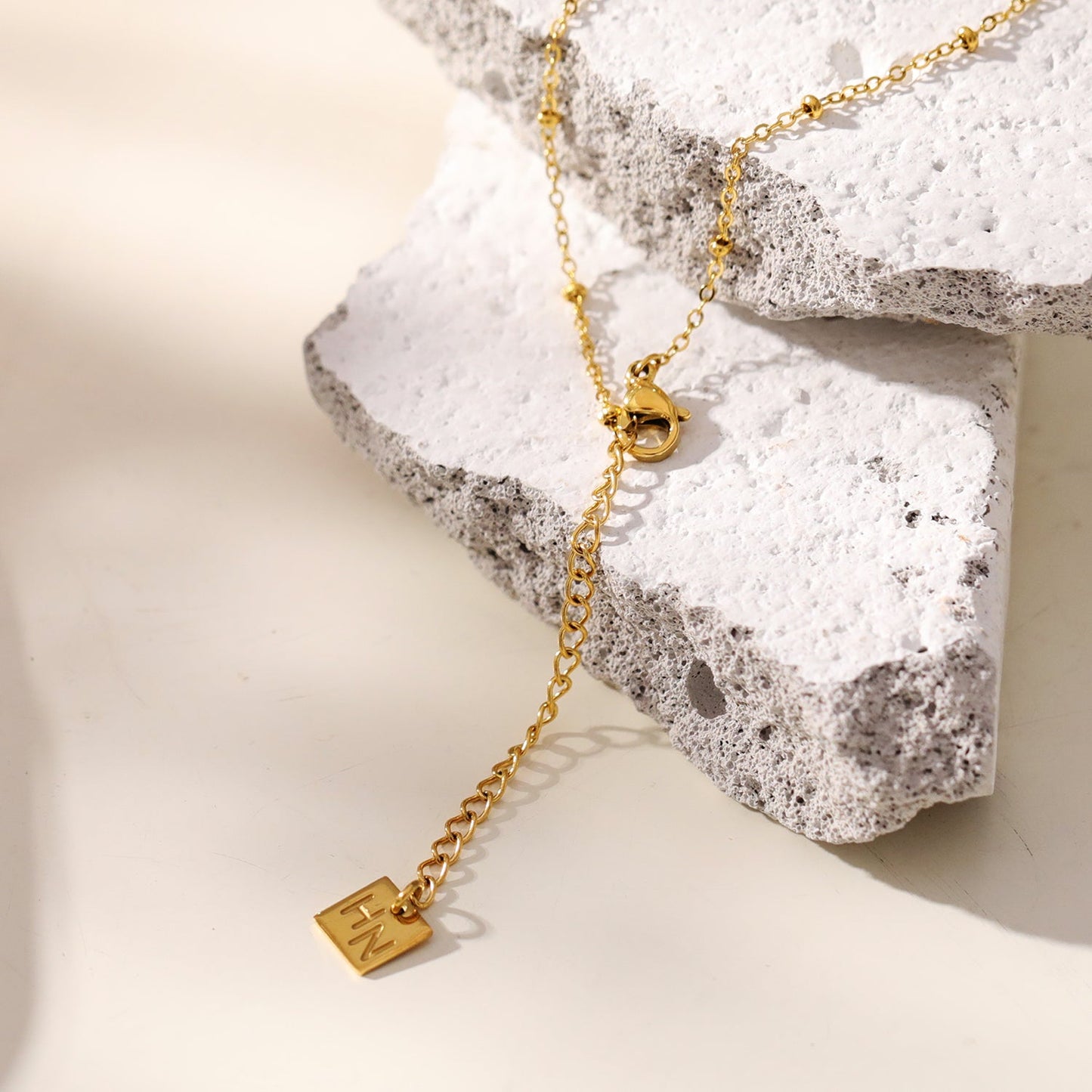 CHAMONIX: Dainty Beaded Chain Necklace with a Zirconia Embedded Textured Cross Pandent