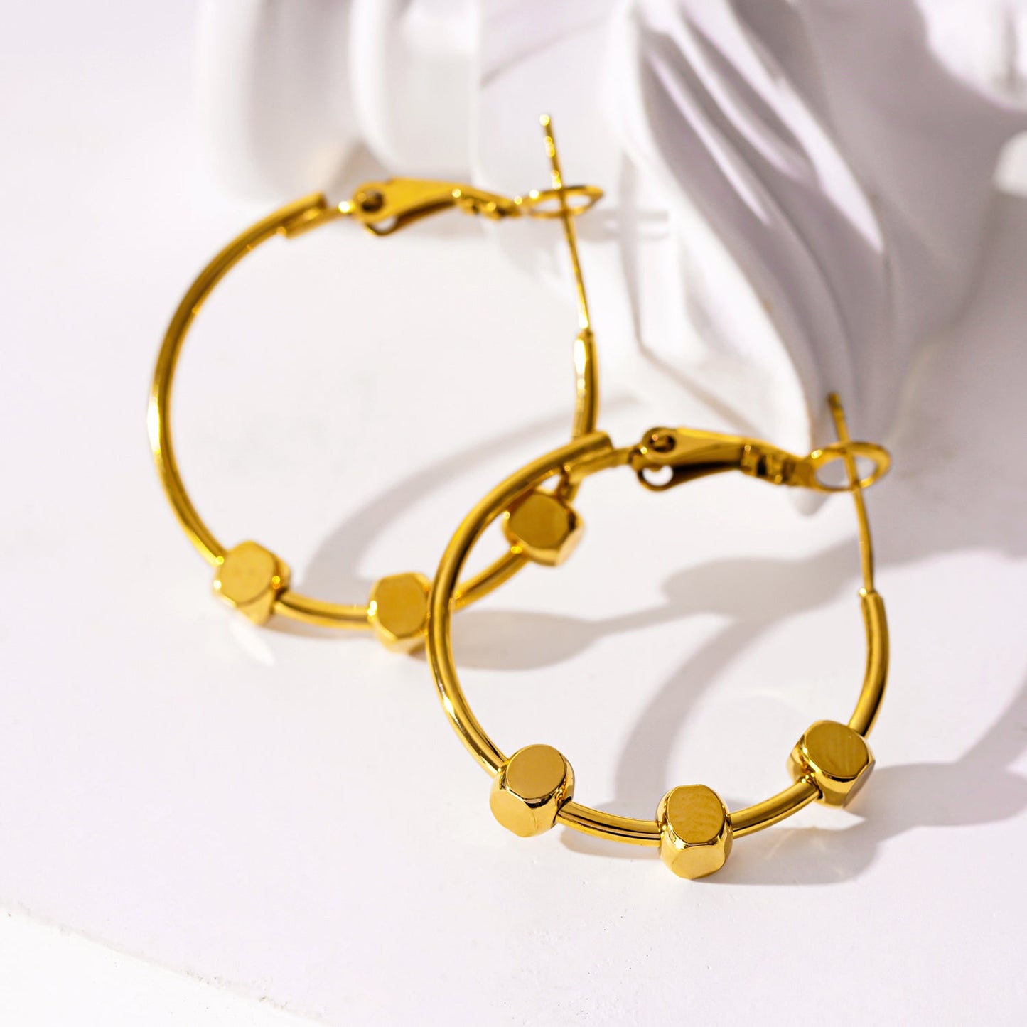 Style MASUYO 1079: Avant-Garde Rounded Hoop Earrings Anchoring a Trio of Square Beads.